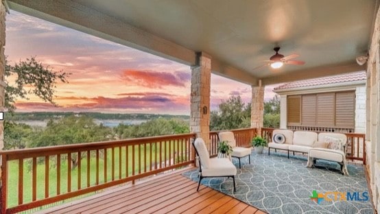 deck at dusk featuring ceiling fan and an outdoor living space