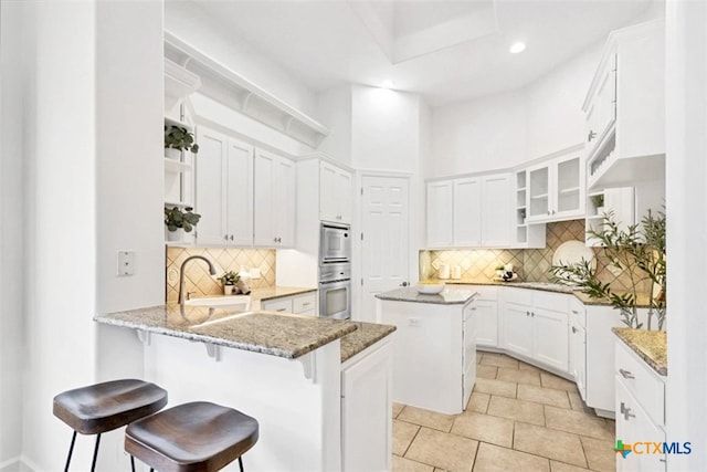 kitchen featuring sink, a breakfast bar area, a center island, white cabinets, and kitchen peninsula