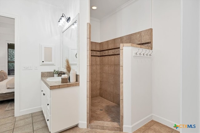 bathroom with vanity, tile patterned flooring, crown molding, and tiled shower