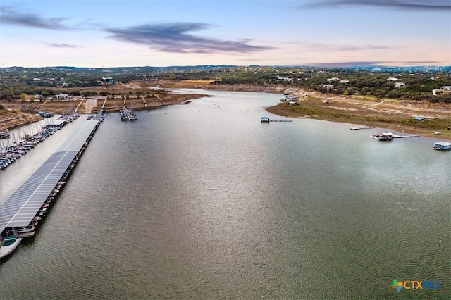 aerial view at dusk featuring a water view