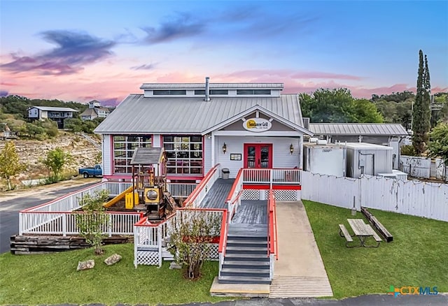 playground at dusk featuring a yard and french doors