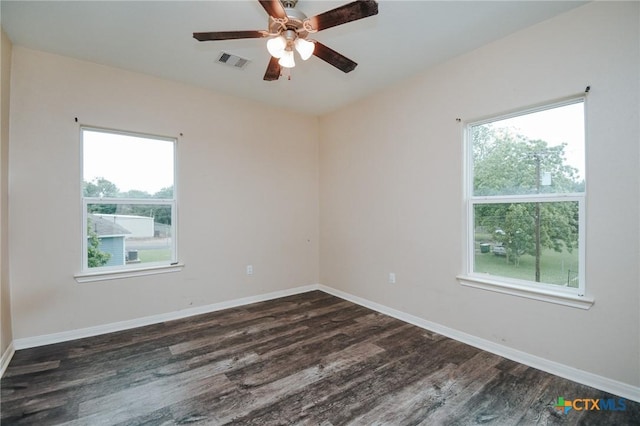 spare room featuring visible vents, a ceiling fan, plenty of natural light, and dark wood-style floors