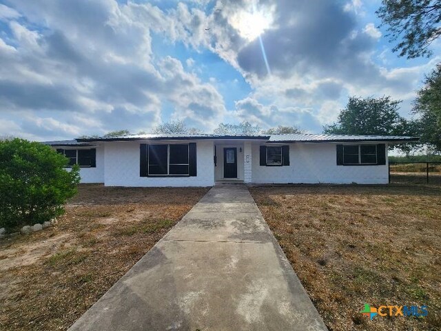 ranch-style home with metal roof and stucco siding