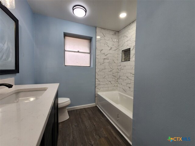 bathroom with bathtub / shower combination, toilet, vanity, wood finished floors, and baseboards