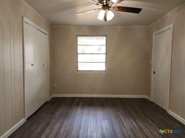 unfurnished bedroom with dark wood-style floors, a closet, baseboards, and crown molding