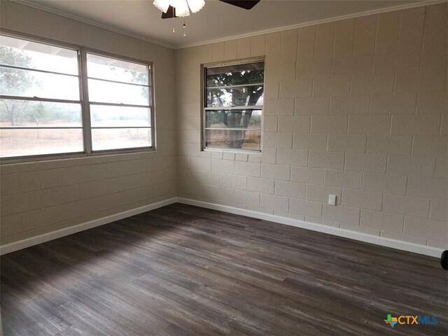 unfurnished room with crown molding, dark wood finished floors, baseboards, and a ceiling fan