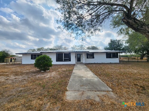 ranch-style house with fence, metal roof, and stucco siding