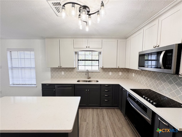 kitchen featuring white cabinetry, sink, black appliances, backsplash, and light hardwood / wood-style flooring