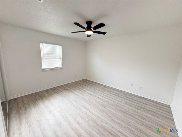 empty room with a textured ceiling, light wood-type flooring, and ceiling fan