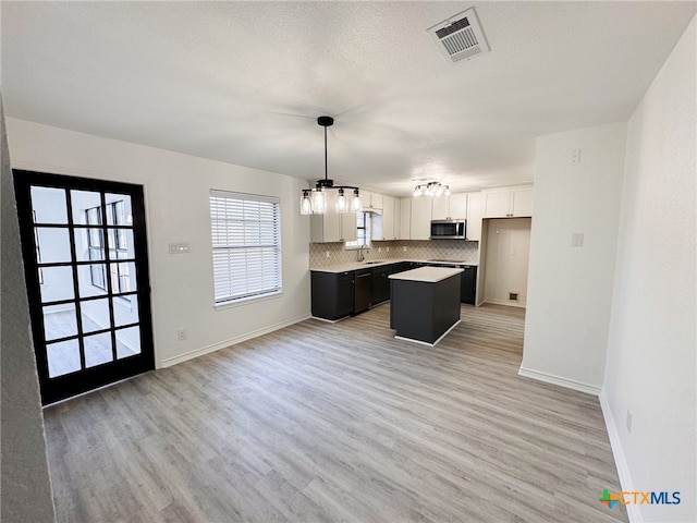 kitchen featuring a center island, backsplash, pendant lighting, white cabinets, and light hardwood / wood-style flooring