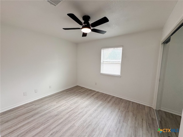 unfurnished bedroom featuring a textured ceiling, light hardwood / wood-style floors, ceiling fan, and a closet