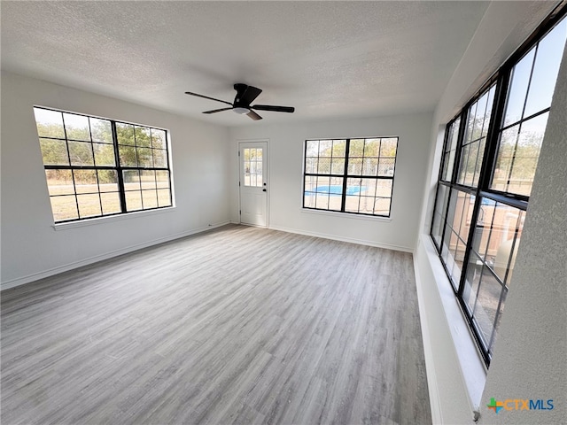 interior space featuring ceiling fan, a textured ceiling, and light wood-type flooring