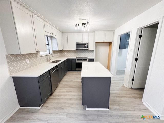 kitchen featuring white cabinetry, sink, appliances with stainless steel finishes, a textured ceiling, and a center island