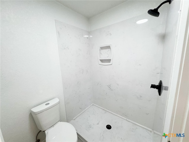 bathroom featuring toilet and a tile shower