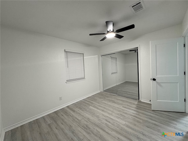 unfurnished bedroom with light wood-type flooring, ceiling fan, and a closet