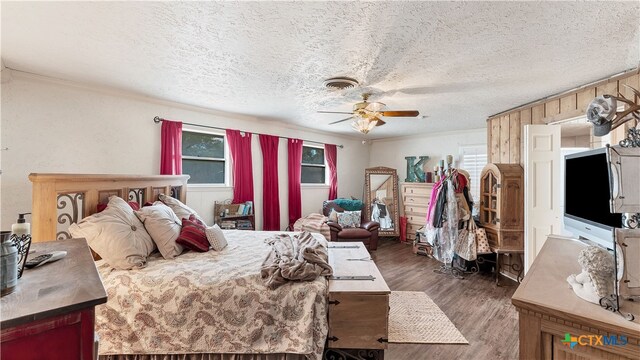 bedroom with ceiling fan, a textured ceiling, and dark hardwood / wood-style flooring