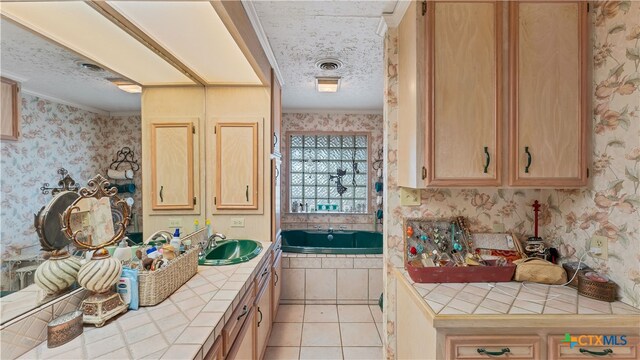 kitchen with a textured ceiling, tile counters, light tile patterned floors, and crown molding