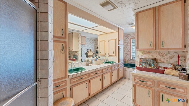 kitchen featuring sink, light brown cabinets, light tile patterned floors, crown molding, and tile counters