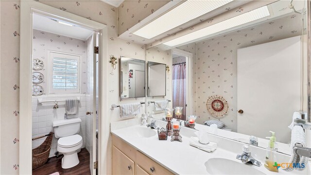 bathroom with toilet, vanity, hardwood / wood-style floors, and tile walls