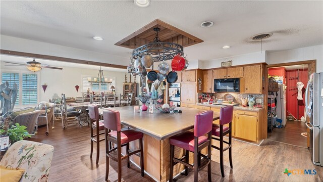 dining area featuring a textured ceiling, ceiling fan with notable chandelier, and hardwood / wood-style flooring