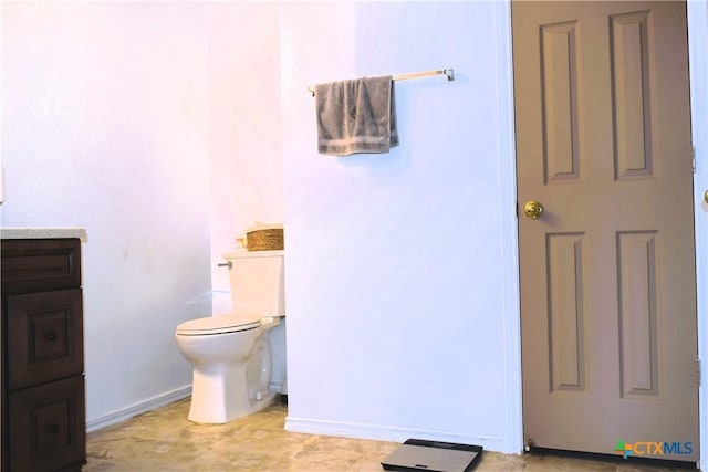 bathroom featuring toilet, vanity, and baseboards