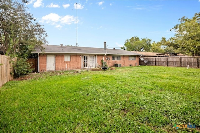 rear view of house featuring cooling unit and a lawn