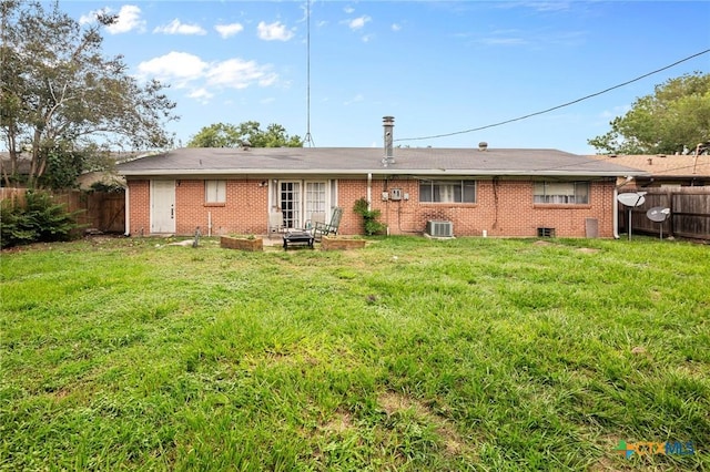 rear view of property featuring a yard and cooling unit