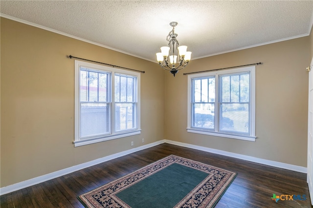 empty room with a textured ceiling, an inviting chandelier, dark hardwood / wood-style flooring, and crown molding