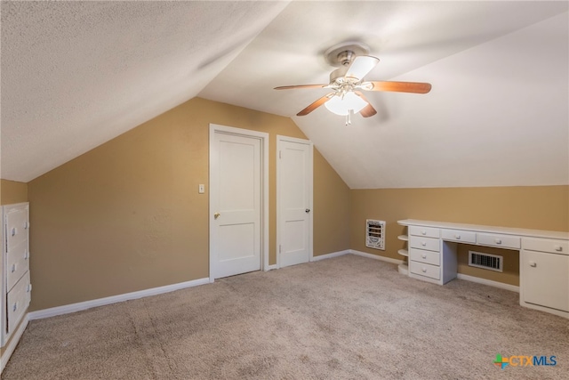 additional living space with lofted ceiling, a textured ceiling, light carpet, heating unit, and ceiling fan