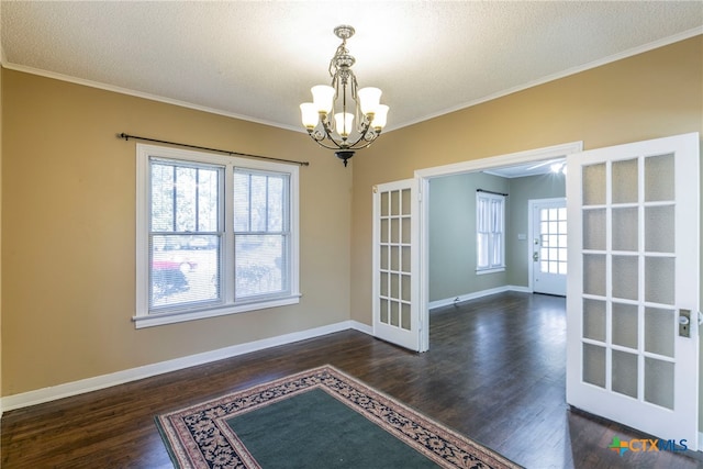 unfurnished dining area featuring french doors, crown molding, a textured ceiling, dark hardwood / wood-style floors, and a chandelier