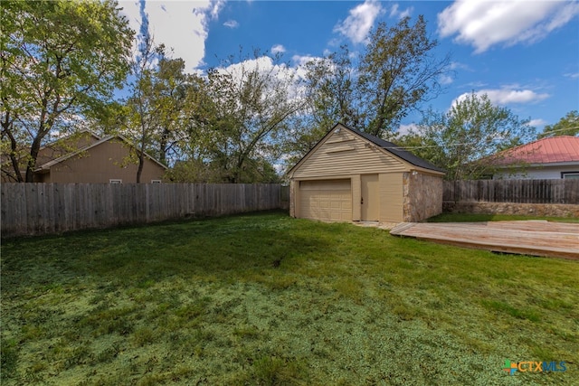 view of yard featuring a garage, a wooden deck, and an outbuilding