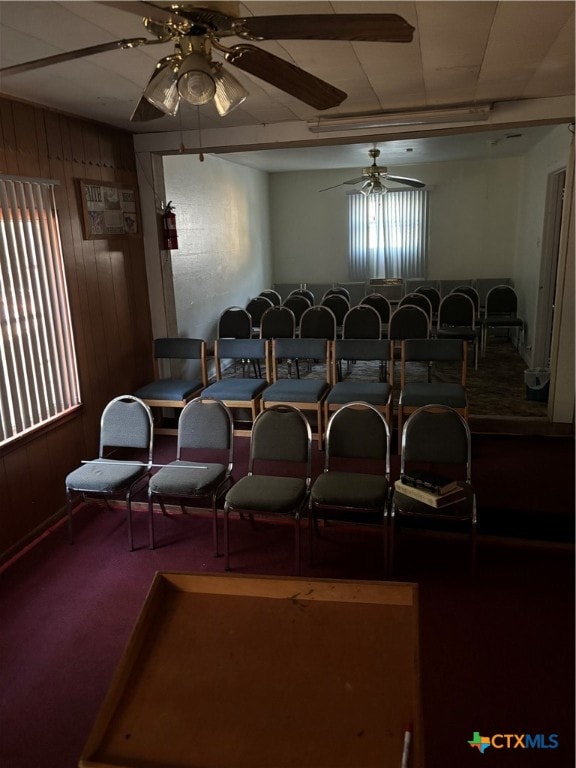 carpeted cinema featuring ceiling fan and wooden walls