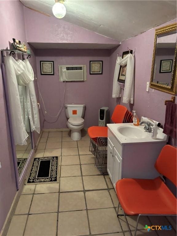 bathroom featuring toilet, vanity, tile patterned flooring, vaulted ceiling, and a wall unit AC