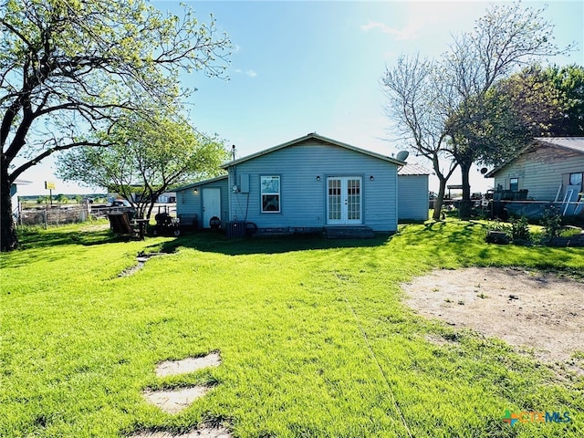 rear view of house with french doors, central air condition unit, and a lawn