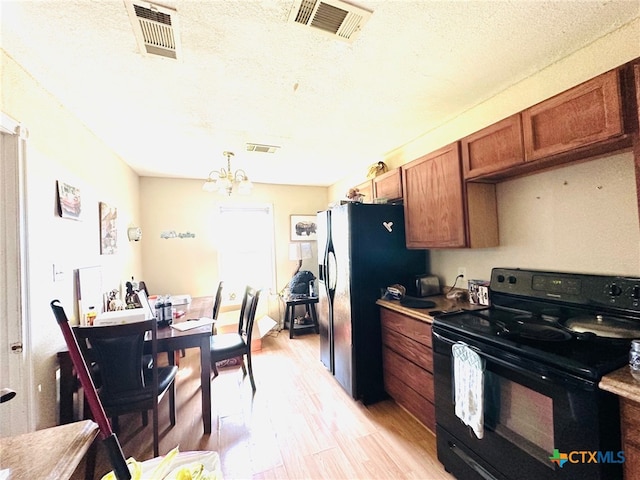 kitchen featuring light hardwood / wood-style floors, black appliances, a textured ceiling, decorative light fixtures, and a chandelier