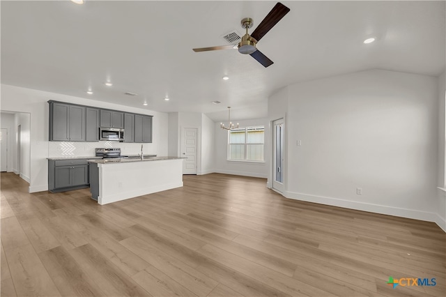 kitchen with gray cabinetry, light hardwood / wood-style flooring, a center island with sink, ceiling fan with notable chandelier, and appliances with stainless steel finishes