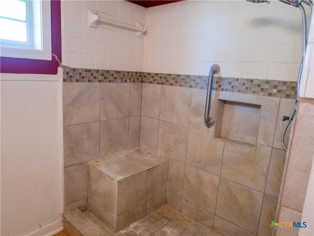 full bathroom featuring a tile shower and wainscoting