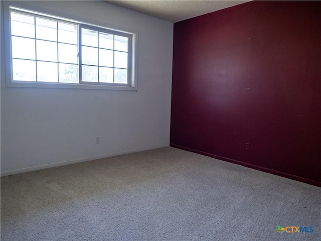 spare room with carpet floors, baseboards, and a textured ceiling