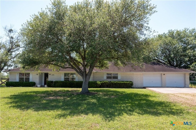 view of front of house featuring an attached garage, concrete driveway, a front lawn, and brick siding