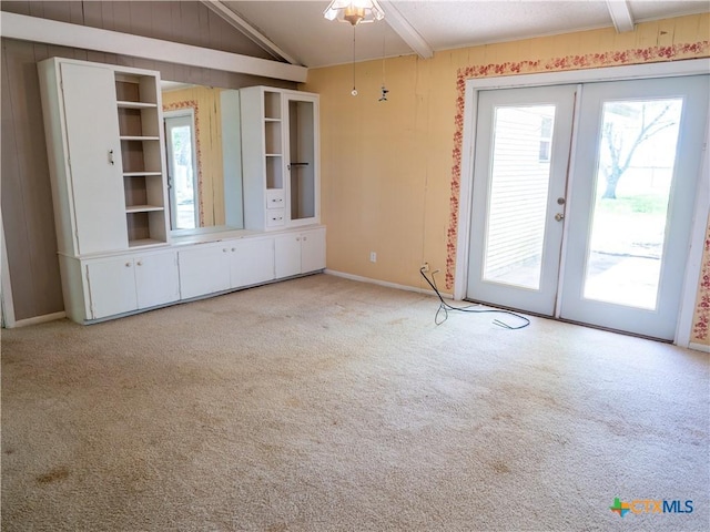 unfurnished living room with lofted ceiling, french doors, carpet floors, and ceiling fan