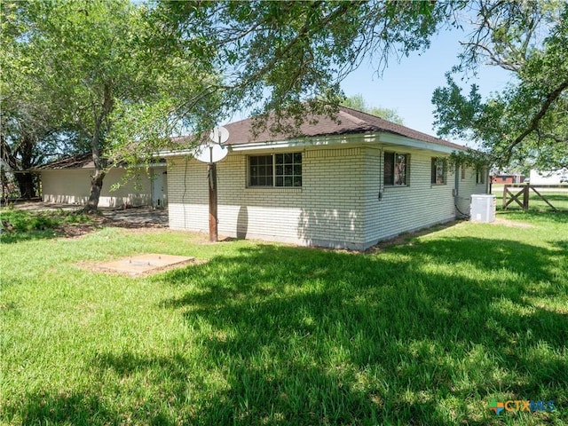 view of side of home featuring a yard, fence, and brick siding