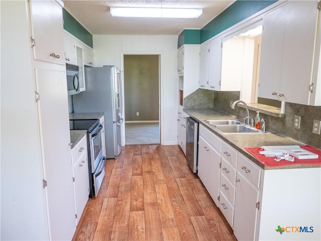 kitchen featuring a sink, white cabinets, appliances with stainless steel finishes, and light wood-style flooring