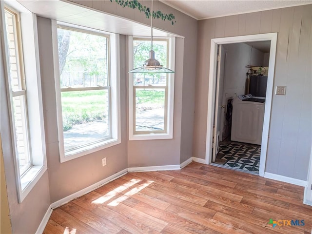 interior space featuring light wood-type flooring, separate washer and dryer, baseboards, and ornamental molding