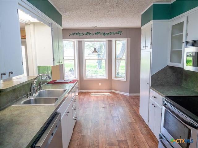 kitchen featuring a textured ceiling, a sink, white cabinetry, and stainless steel appliances