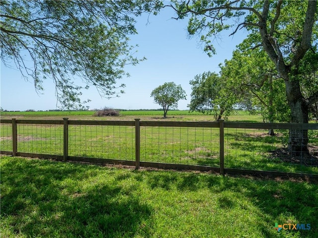 view of yard with fence and a rural view