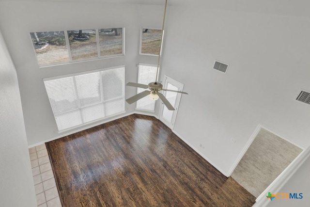 unfurnished living room with a towering ceiling, hardwood / wood-style floors, and ceiling fan