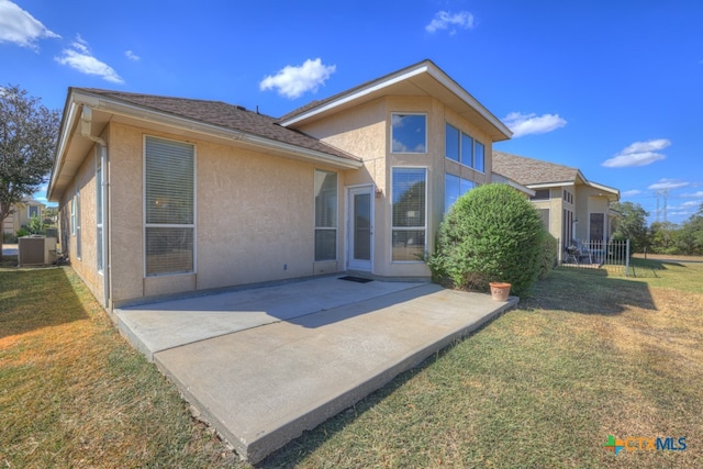 rear view of house featuring cooling unit, a patio area, and a lawn