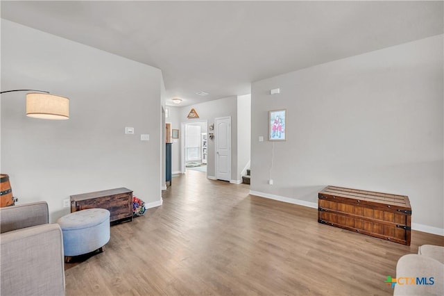 living area with stairway, baseboards, and wood finished floors