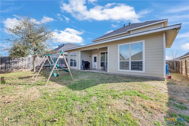 rear view of house featuring a patio, a playground, a yard, and a fenced backyard