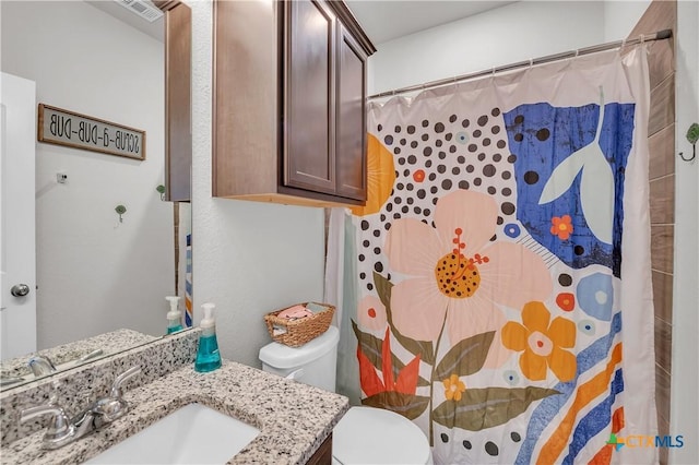 full bathroom featuring vanity, curtained shower, toilet, and visible vents